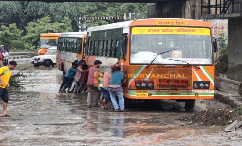 रेलवे अंडर पास के नीचे भरे पानी में फंसी रोडवेज की बस को खुद ही धक्का देकर बाहर निकालते बस यात्री व स्थानीय लोग